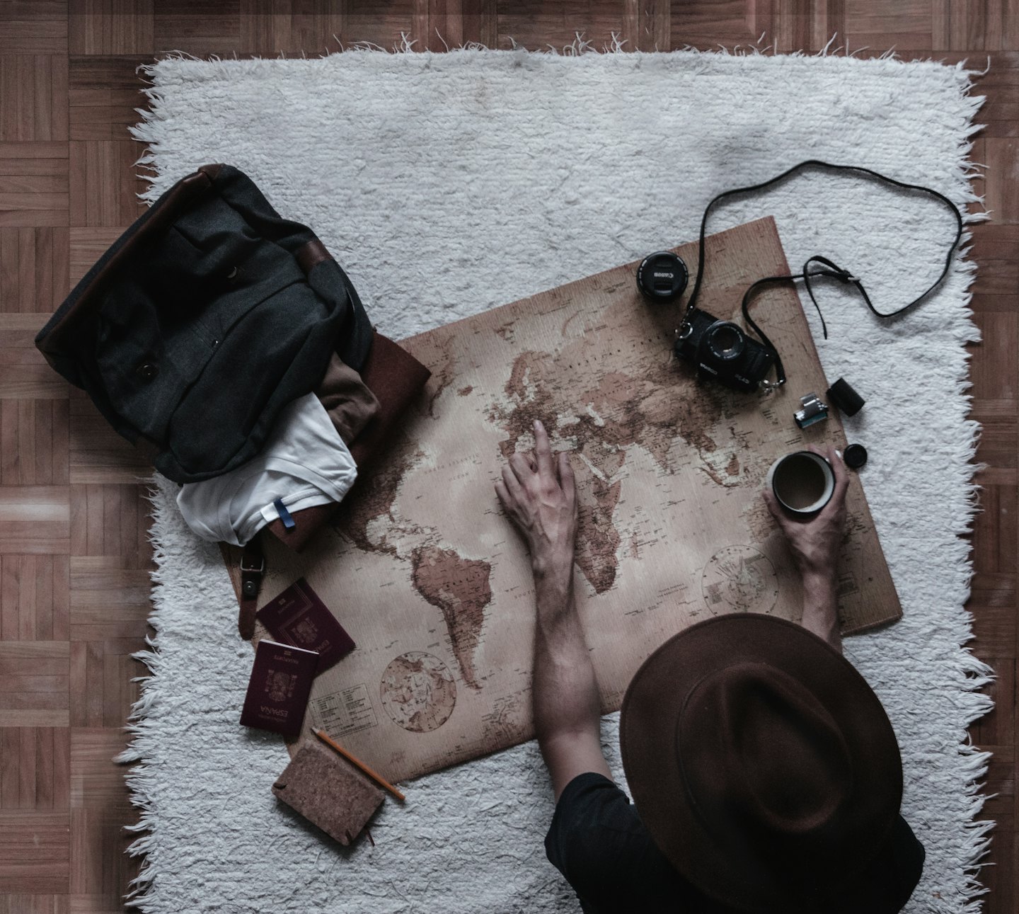 A person points at a world map surrounded by travel gear.